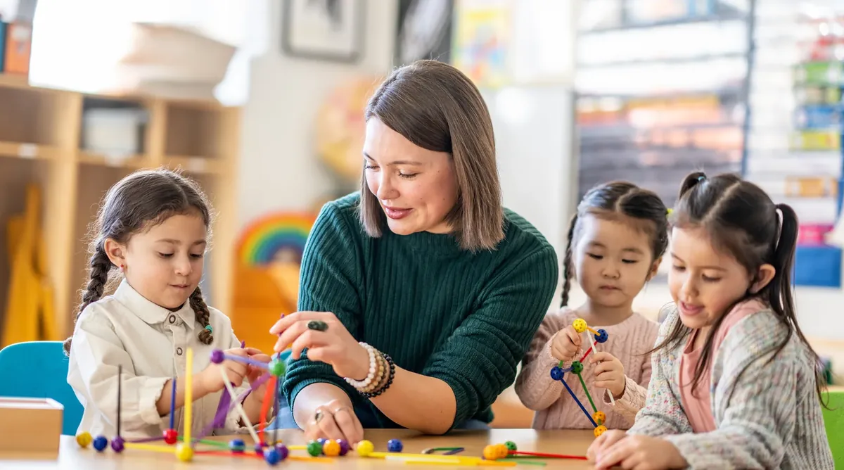 Early years educator supporting children at play